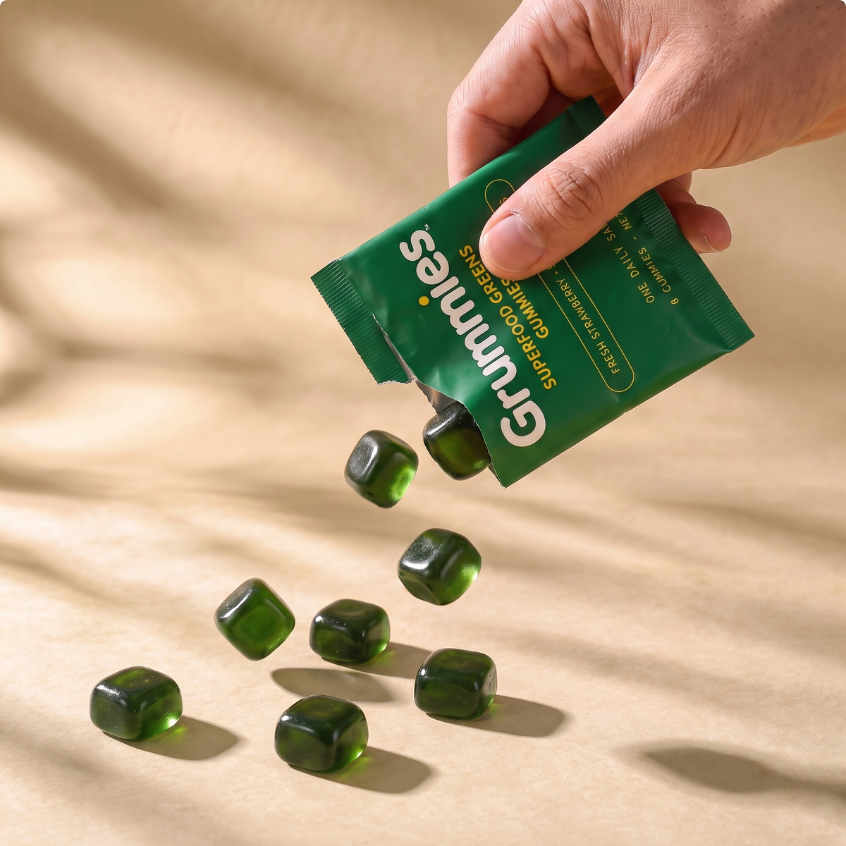 Grummies pouch standing with one sachet leaning against it and a loose scatter of gummies